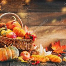 Thanksgiving pumpkins with fruits and falling leaves on rustic wooden table